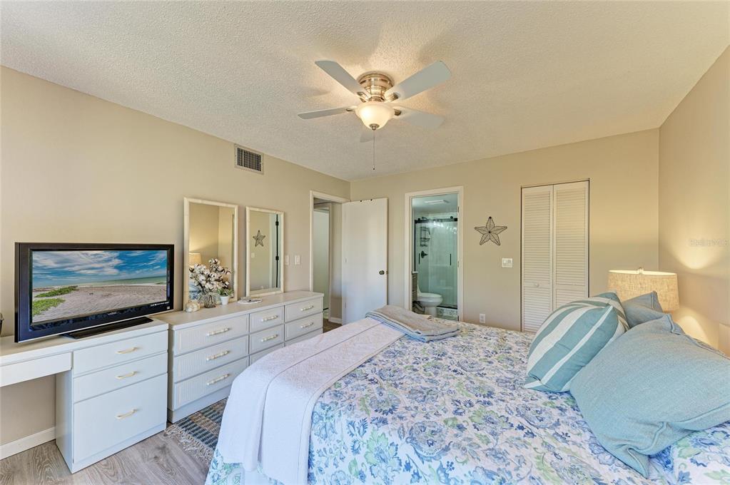 756 White Pine Tree Road, Unit 210 Venice, FL 34285 - Photo 18 of 55 a bedroom with a large bed a flat tv screen and a dresser