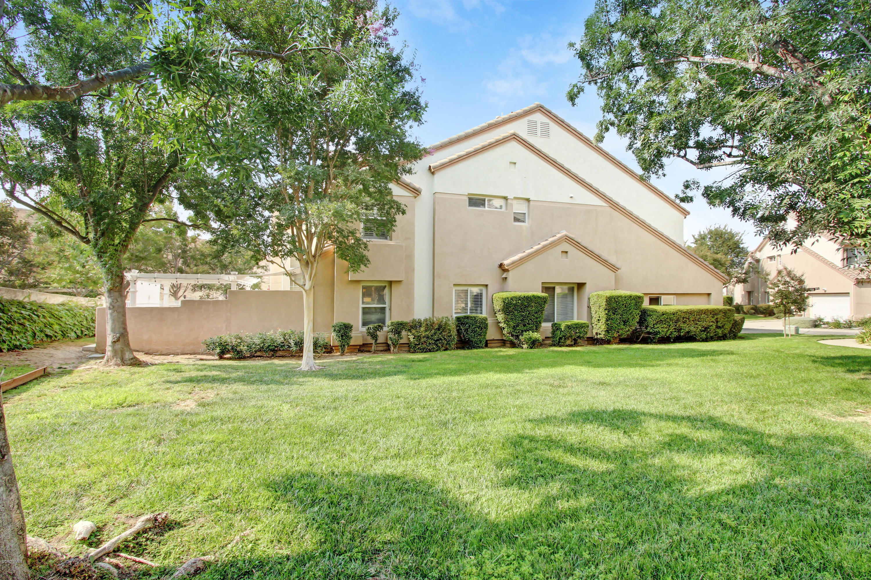 697 Lariate Lane, Unit A Simi Valley, CA 93065 - Photo 24 of 26 a view of a white house with a big yard and large trees