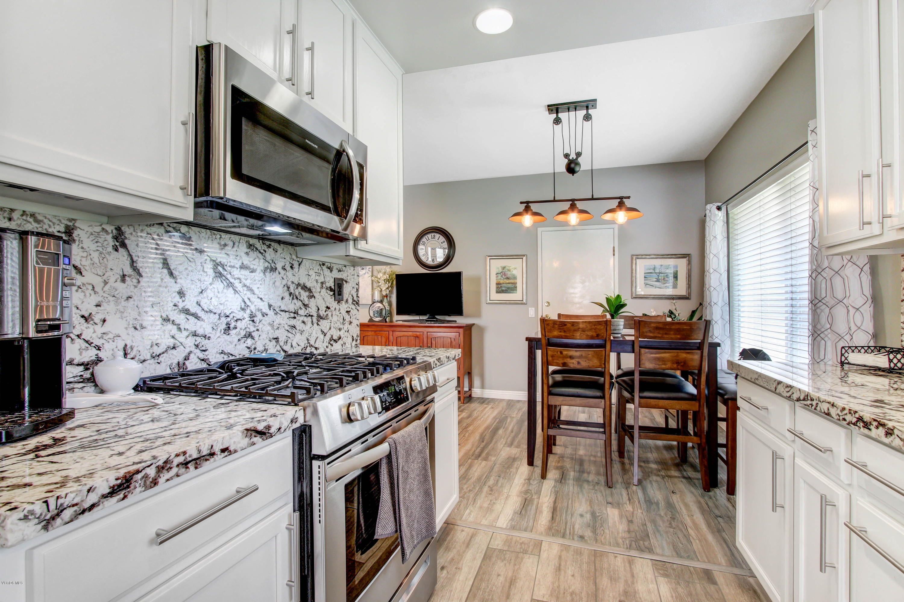 697 Lariate Lane, Unit A Simi Valley, CA 93065 - Photo 8 of 26 a kitchen with stainless steel appliances granite countertop a stove top oven a sink dishwasher a dining table and chairs with wooden floor