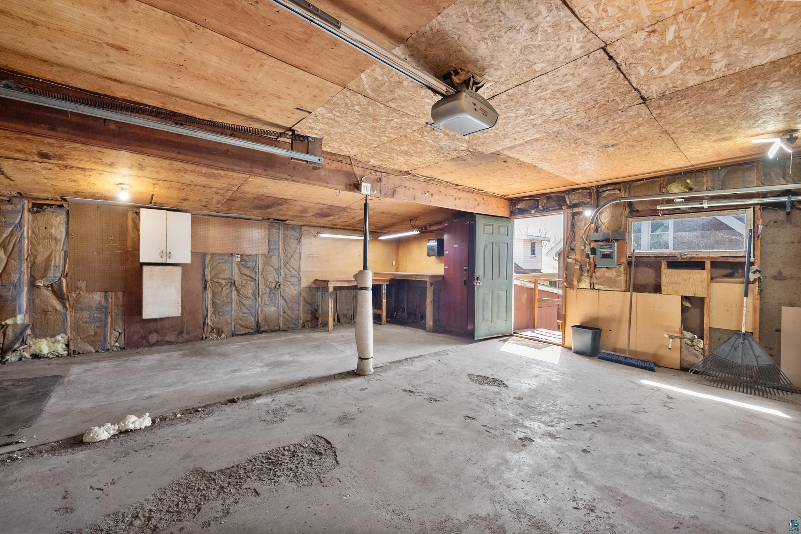 3067 Restormel Street Duluth, MN 55806 - Photo 22 of 25 Spacious garage featuring a concrete floor, exposed wood ceiling, built-in workbench, and wall-mounted cabinetry