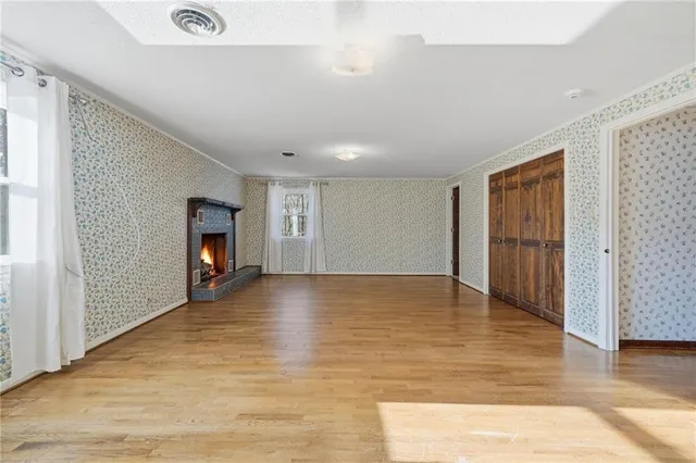 a view of empty room with wooden floor and fireplace