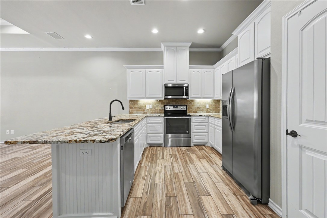302 Cooper Road, Unit E2 Odem, TX 78370 - Photo 6 of 24 a kitchen with kitchen island granite countertop stainless steel appliances a sink stove refrigerator and cabinets