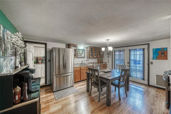 a kitchen with stainless steel appliances granite countertop a dining table chairs refrigerator and sink