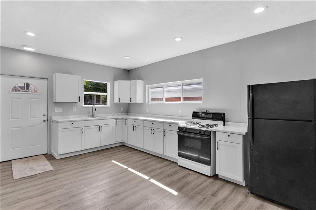 1406 Broadway Avenue McKees Rocks, PA 15136 - Photo 11 of 28 a kitchen with a stove top oven a sink dishwasher a refrigerator and white cabinets with wooden floor
