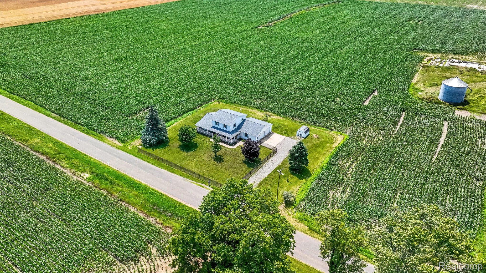 996 Arbogast Road Union City, MI 49094 - Photo 31 of 34 Aerial perspective showcasing a light-colored residence with a dark roof, surrounded by expansive green fields