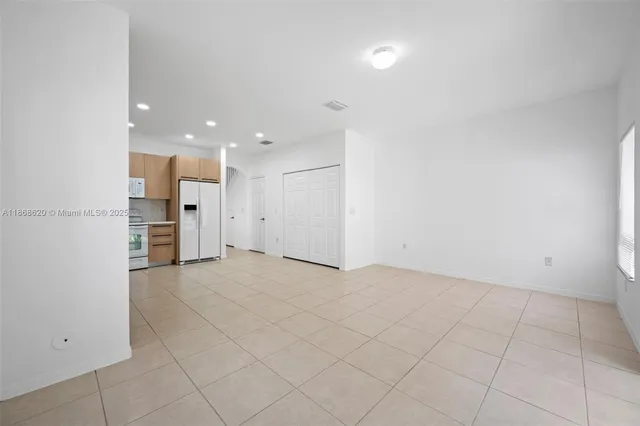 an empty room with kitchen view and windows
