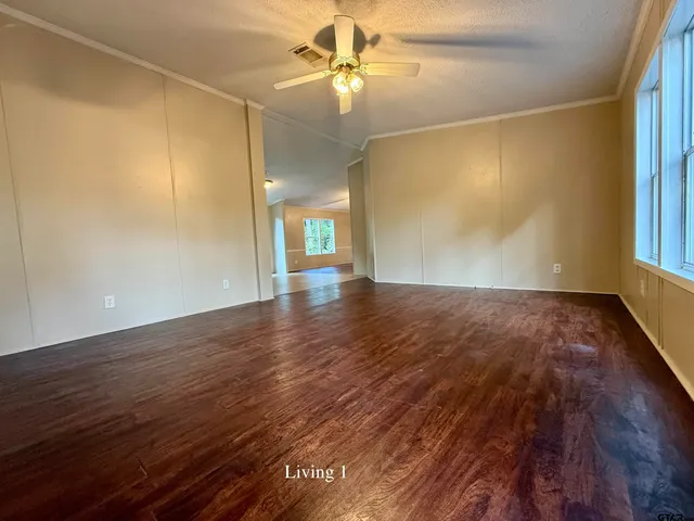 an empty room with wooden floor chandelier and windows