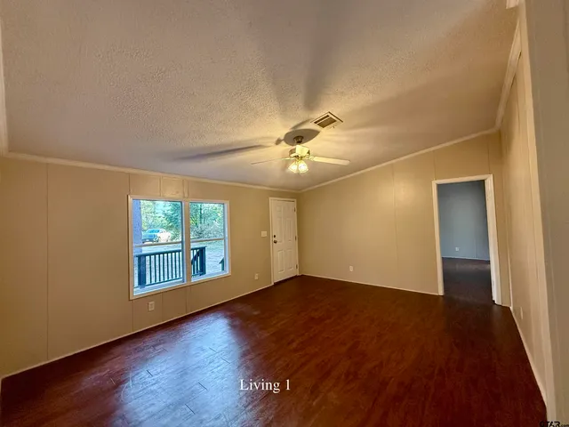 a view of a livingroom with a fireplace a ceiling fan and wooden floor