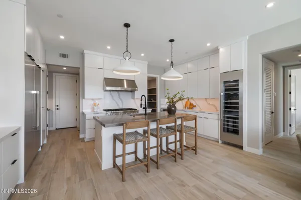 a view of a dining room and livingroom with furniture wooden floor kitchen chandelier