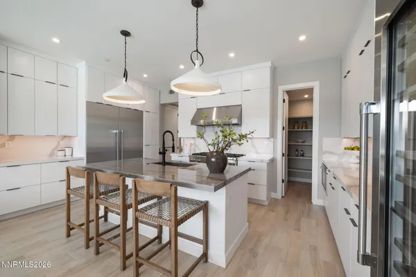 a kitchen with stainless steel appliances a dining table chairs refrigerator and sink