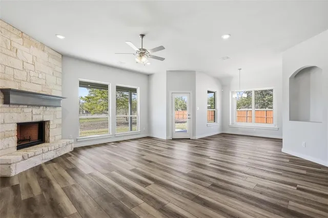 a view of an empty room with wooden floor fireplace and a window