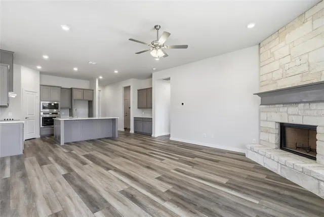 a view of an empty room with kitchen and fireplace