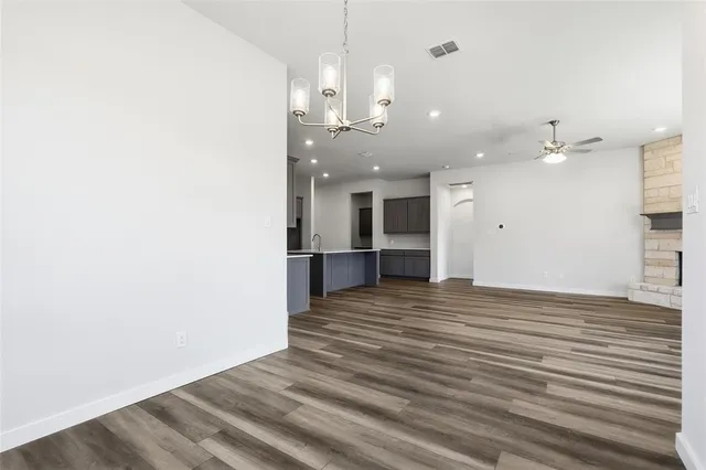 an empty room with wooden floor and kitchen view