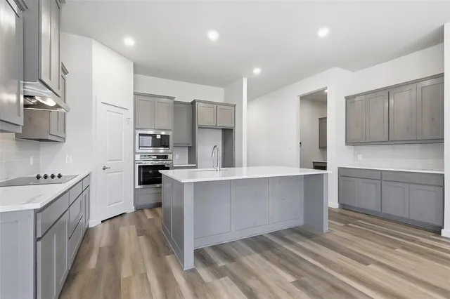 a kitchen with stainless steel appliances a sink dishwasher stove refrigerator and cabinets with wooden floor