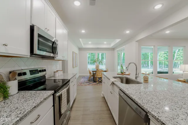 a kitchen with stainless steel appliances granite countertop sink stove microwave and refrigerator