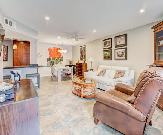 a living room with furniture kitchen view and a large window