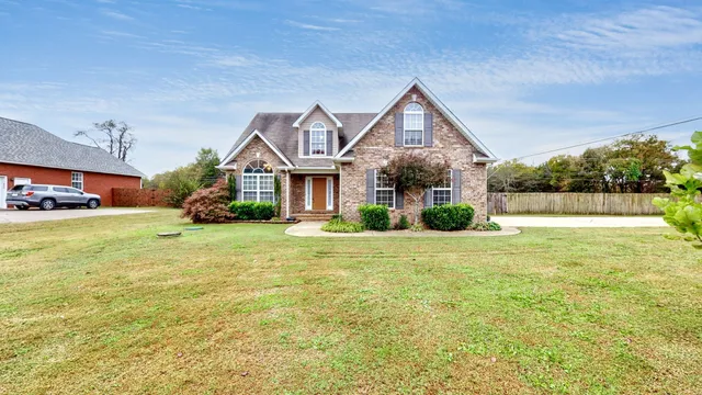a front view of a house with a garden and trees