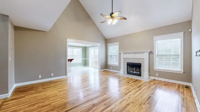 a view of an empty room with wooden floor fireplace and a window
