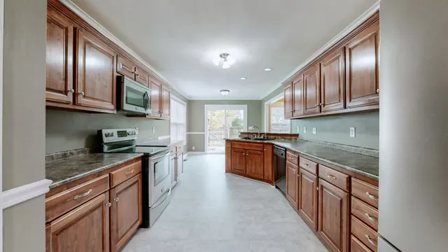 a kitchen with stainless steel appliances granite countertop a stove top oven a sink dishwasher a refrigerator and cabinets with wooden floor