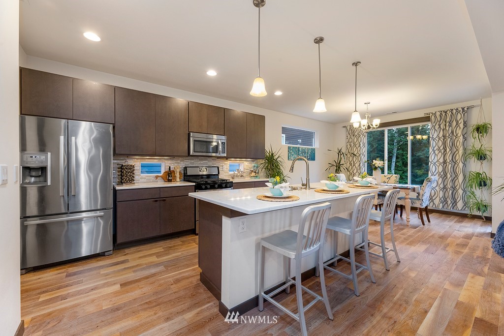 17507 3rd Avenue Southeast Bothell, WA 98012 - Photo 8 of 40 a kitchen with stainless steel appliances granite countertop a refrigerator a stove top oven a sink dishwasher a dining table and chairs with wooden floor