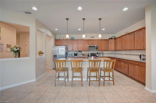 a kitchen with stainless steel appliances granite countertop a table chairs sink and cabinets