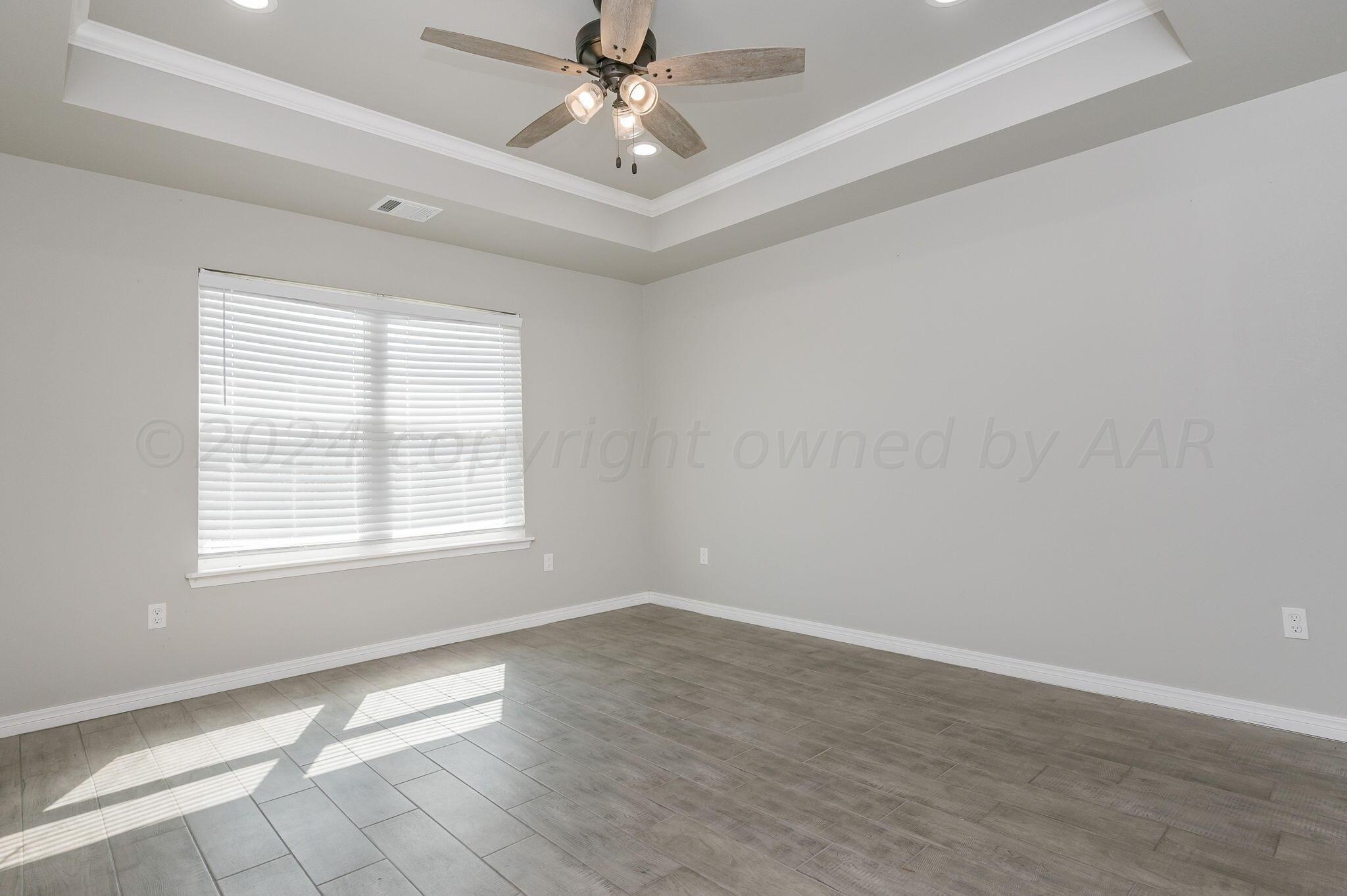13987 Periwinkle Drive, Unit 1 Amarillo, TX 79119 - Photo 11 of 20 an empty room with wooden floor fan and windows