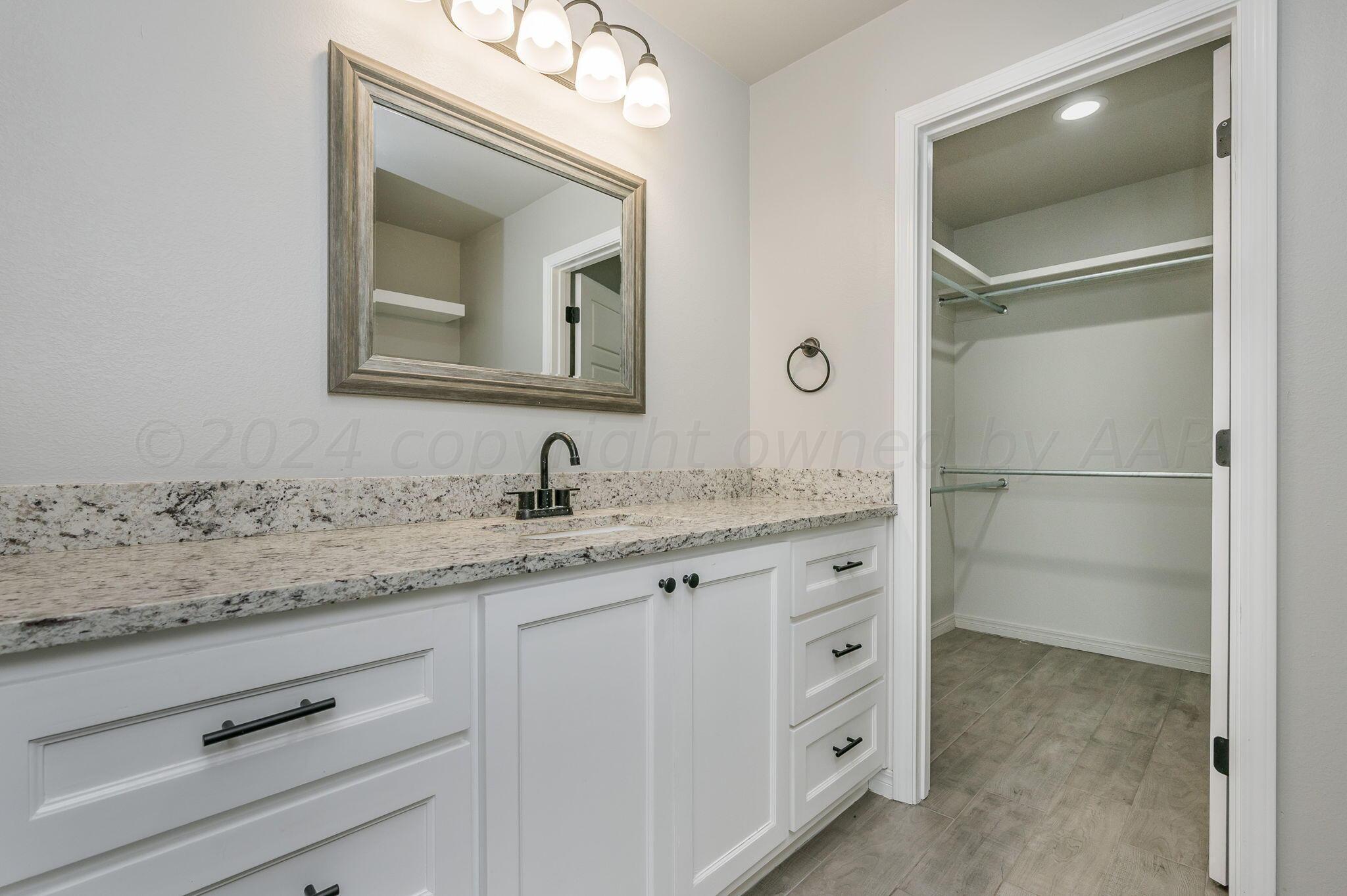 13987 Periwinkle Drive, Unit 1 Amarillo, TX 79119 - Photo 14 of 20 a bathroom with a granite countertop sink vanity and mirror