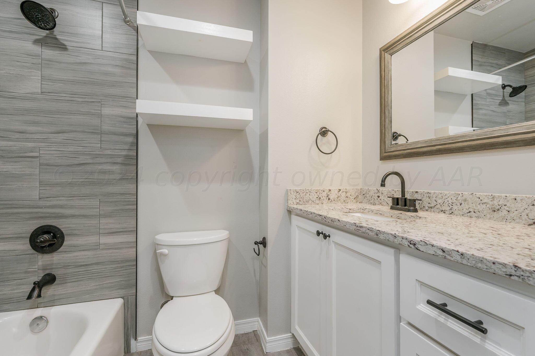 13987 Periwinkle Drive, Unit 1 Amarillo, TX 79119 - Photo 17 of 20 a bathroom with a granite countertop toilet sink and mirror