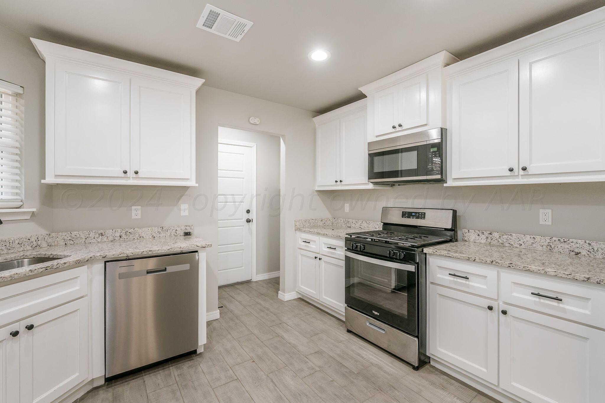 13987 Periwinkle Drive, Unit 1 Amarillo, TX 79119 - Photo 8 of 20 a kitchen with granite countertop white cabinets and stainless steel appliances