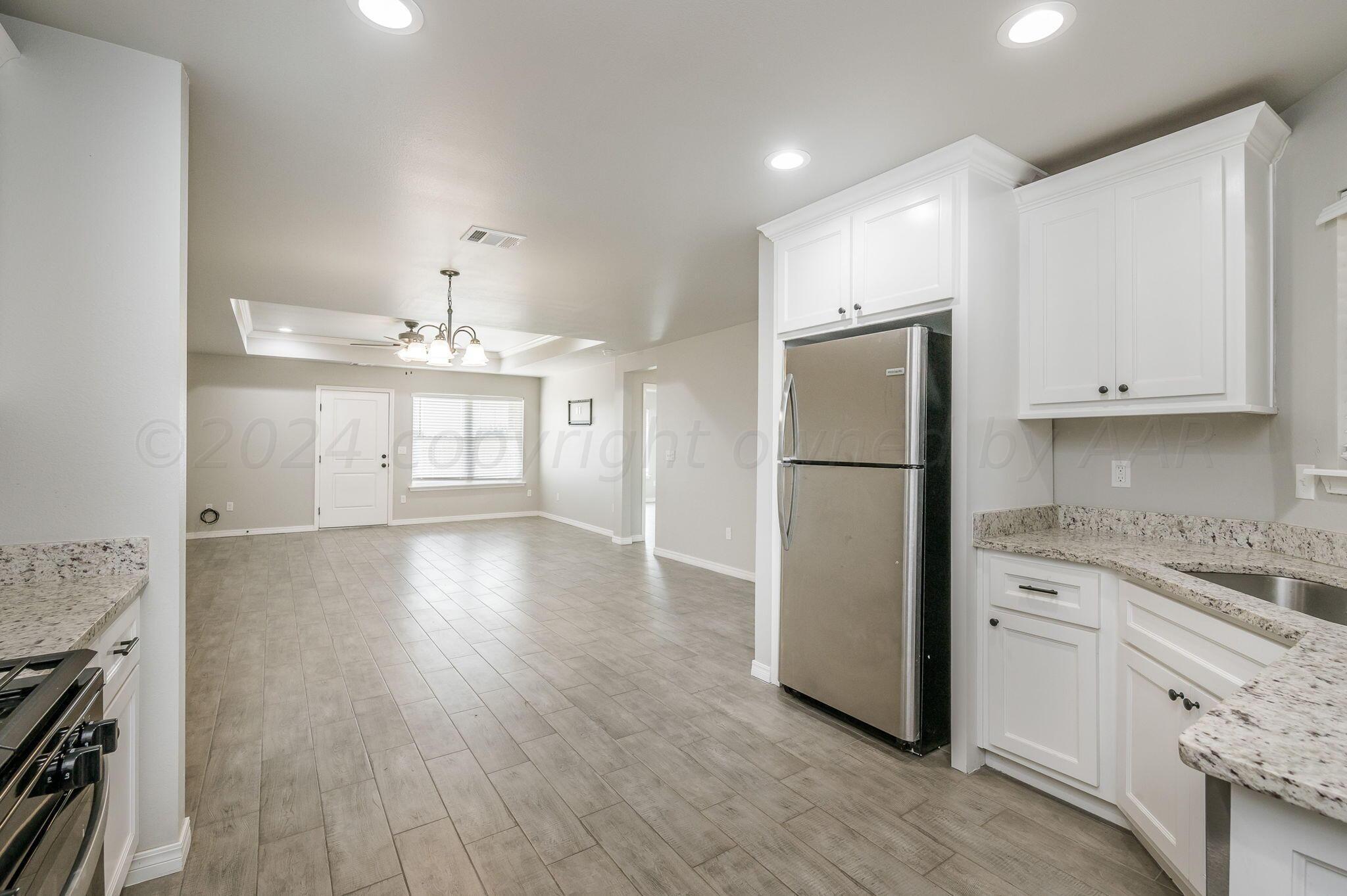 13987 Periwinkle Drive, Unit 1 Amarillo, TX 79119 - Photo 9 of 20 a kitchen with stainless steel appliances granite countertop a refrigerator sink and white cabinets with wooden floor