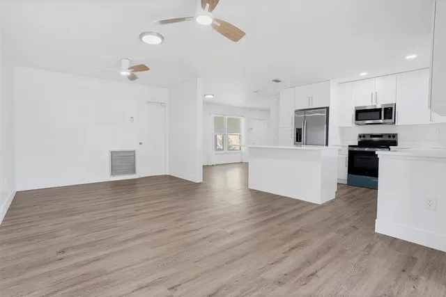 a view of kitchen with microwave a refrigerator and white cabinets