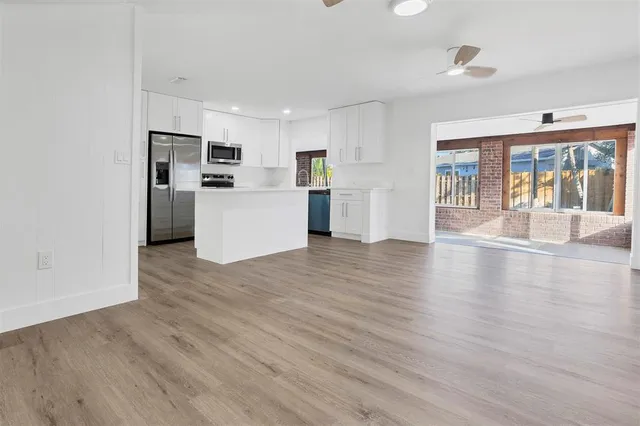 a view of a kitchen with refrigerator and wooden floor