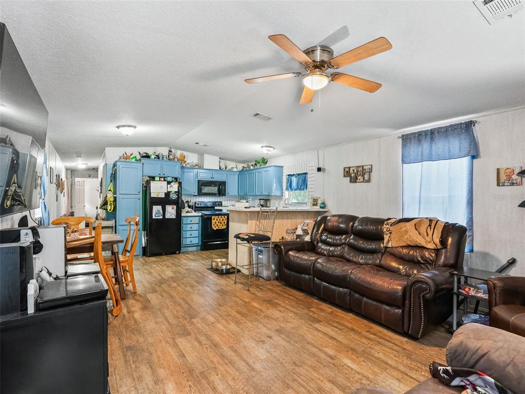 17090 Southeast 173rd Terrace Road Weirsdale, FL 32195 - Photo 29 of 54 a living room with furniture kitchen area and a ceiling fan