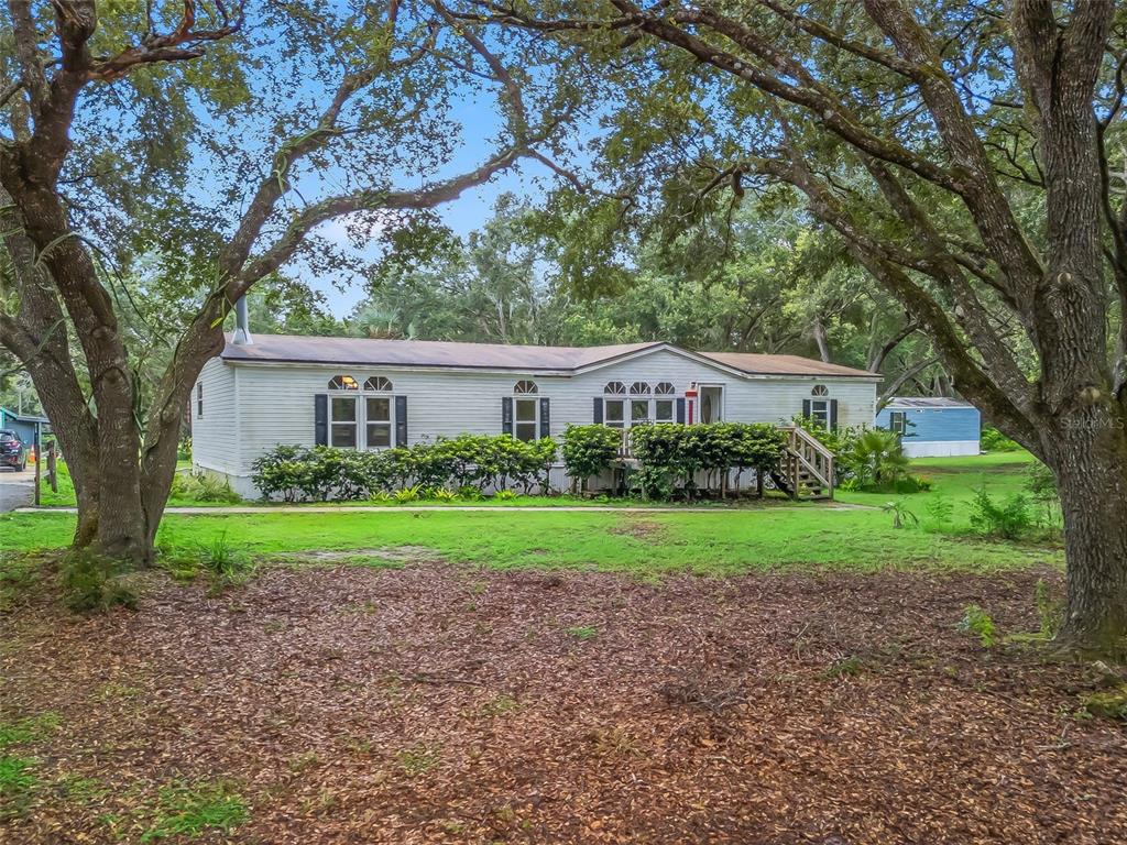 17090 Southeast 173rd Terrace Road Weirsdale, FL 32195 - Photo 3 of 54 a house view with a garden and large trees