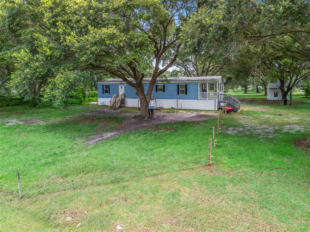 17090 Southeast 173rd Terrace Road Weirsdale, FL 32195 - Photo 46 of 54 a front view of a house with a garden and trees
