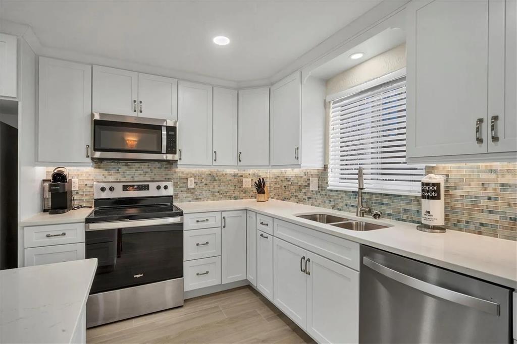 6006 Midnight Pass Road, Unit 36 Sarasota, FL 34242 - Photo 13 of 43 a kitchen with white cabinets appliances a sink and a window