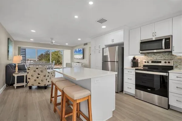 a kitchen with stainless steel appliances kitchen island granite countertop a refrigerator stove microwave and white cabinets