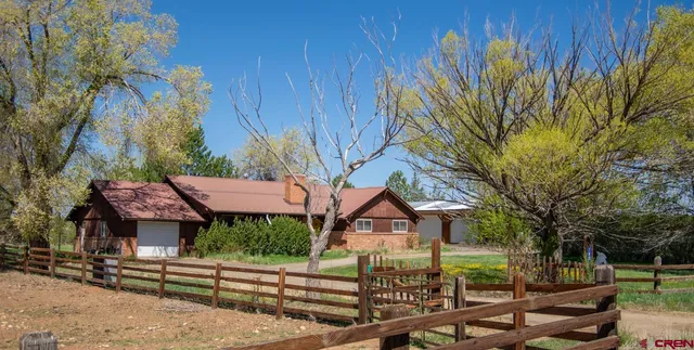 a view of a house with a big yard plants and large tree