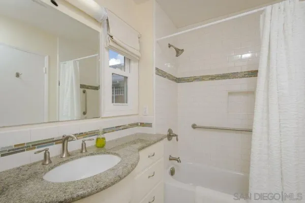 a bathroom with a granite countertop sink mirror and a bathtub