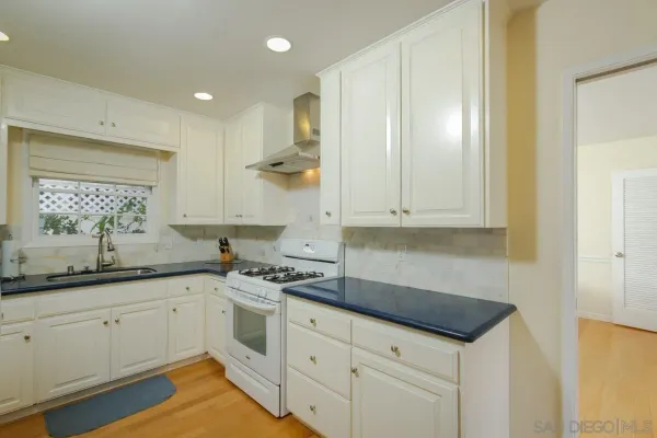 a kitchen with granite countertop white cabinets and white appliances