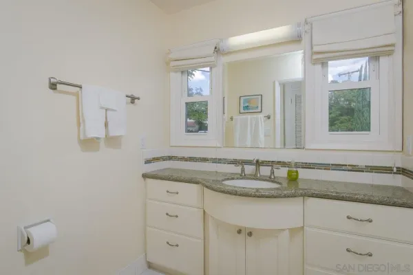 a bathroom with a granite countertop sink and a mirror