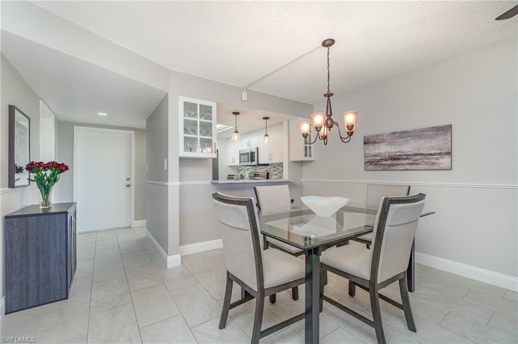 25806 Cockleshell Drive, Unit 115 Bonita Springs, FL 34135 - Photo 5 of 25 a dining room filled chandelier and kitchen view