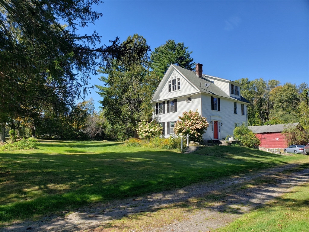 1 Searle Road Huntington, MA 01050 - Photo 2 of 42 a view of a white house in front of a big yard with plants and wooden fence