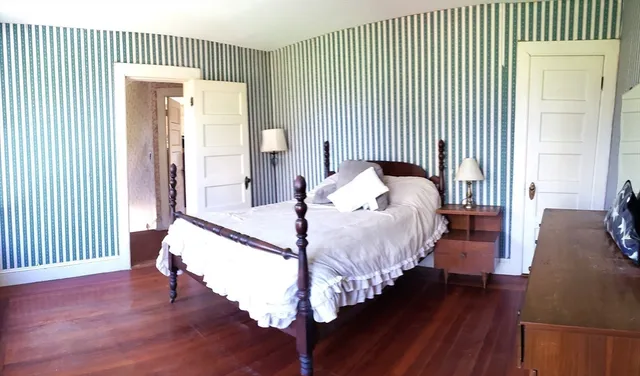 a bed sitting in a spacious bedroom next to a window