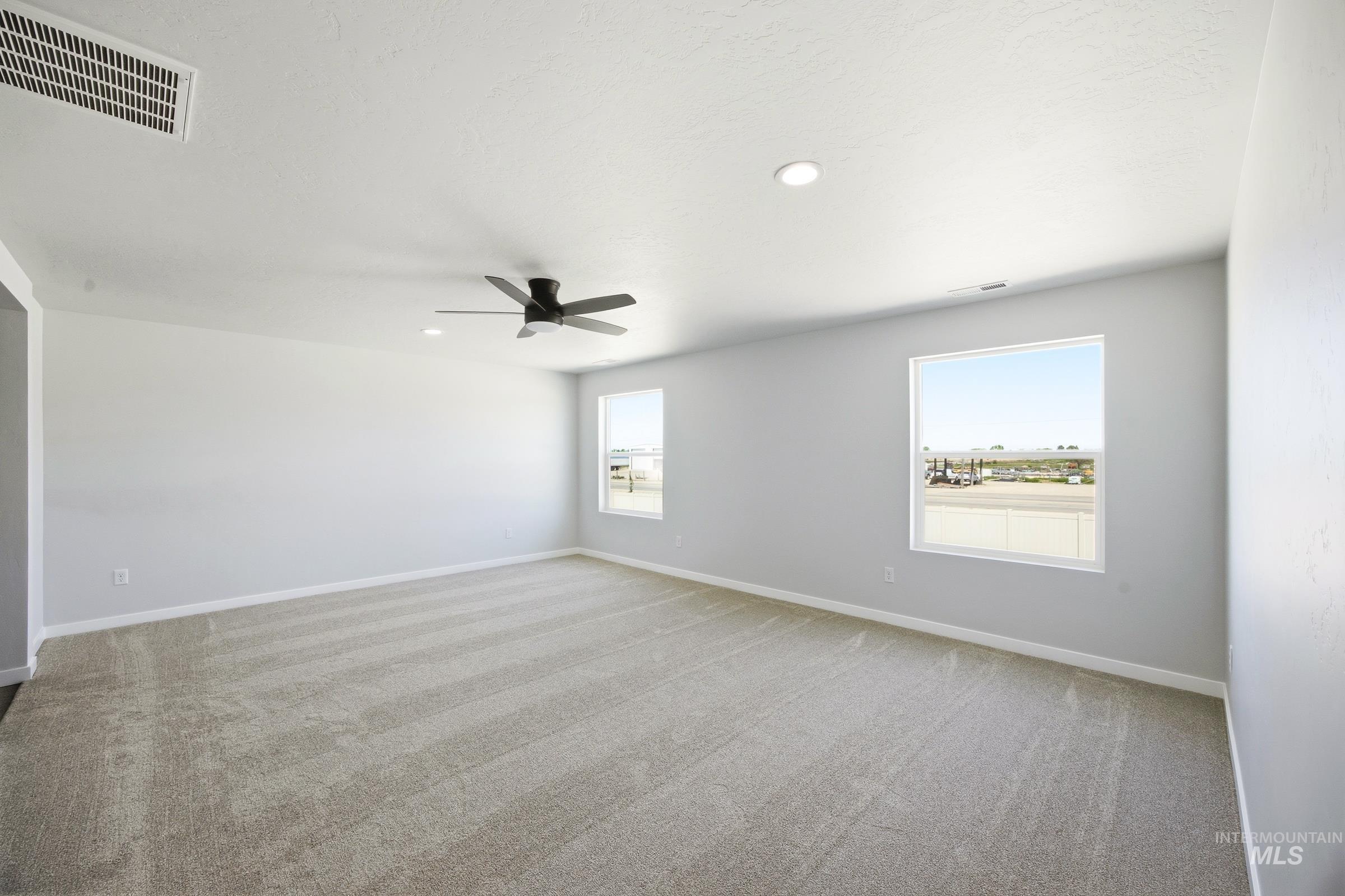 12841 Decatur Street Nampa, ID 83651 - Photo 25 of 30 Spacious room featuring light-colored carpeting, multiple windows, a ceiling fan, and recessed lighting