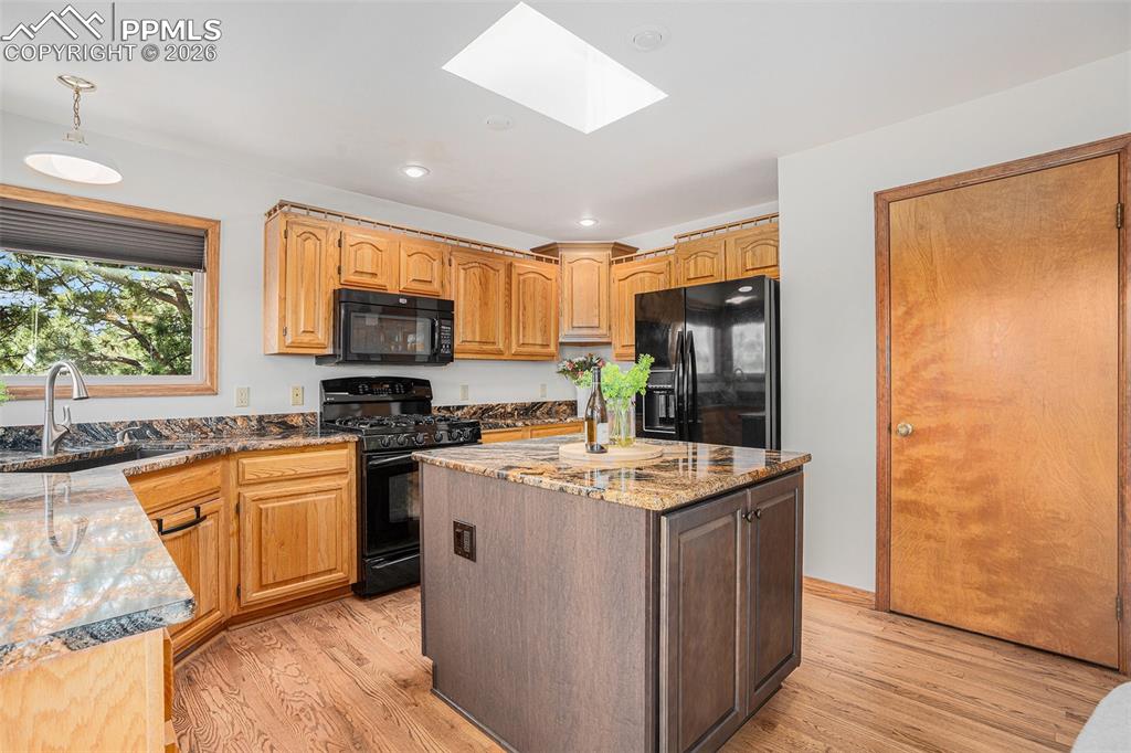 2585 Mohawk Way Monument, CO 80132 - Photo 12 of 49 a kitchen with stainless steel appliances granite countertop a stove top oven a sink dishwasher and a refrigerator with wooden floor