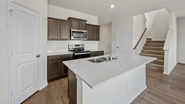 a kitchen with stainless steel appliances a sink a stove top oven a counter space and cabinets