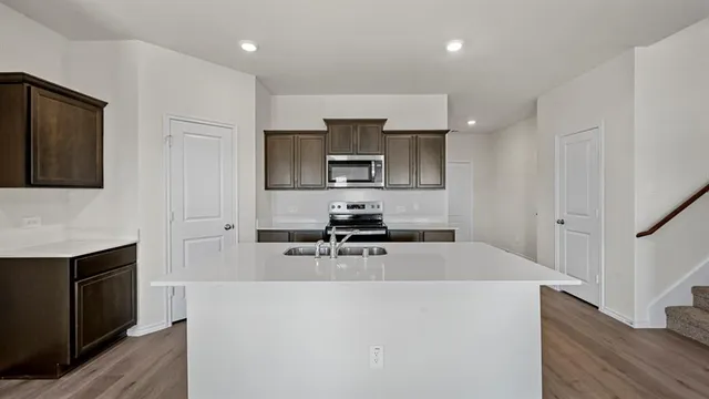 a kitchen with kitchen island a sink appliances and cabinets