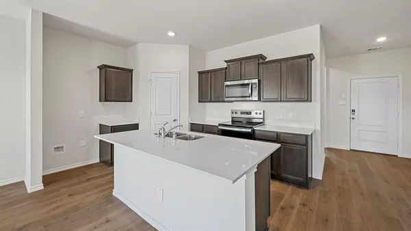 a large kitchen with stainless steel appliances a sink and a refrigerator