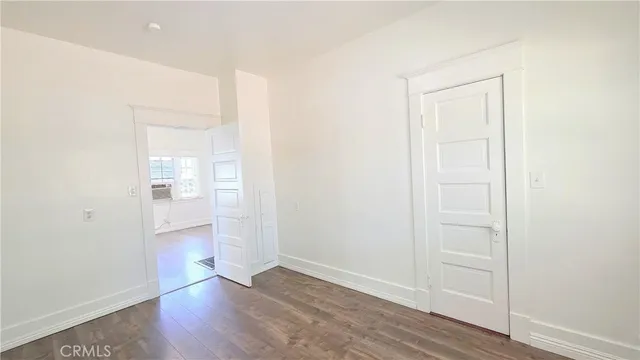 an empty room with wooden floor & windows